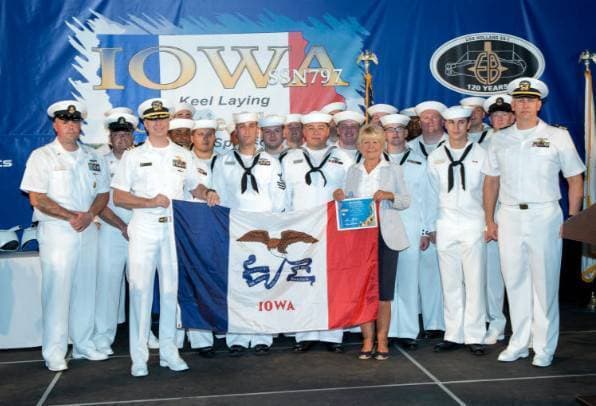 Group of the Iowa SSN 797 Naval crew in uniform holding a flag.