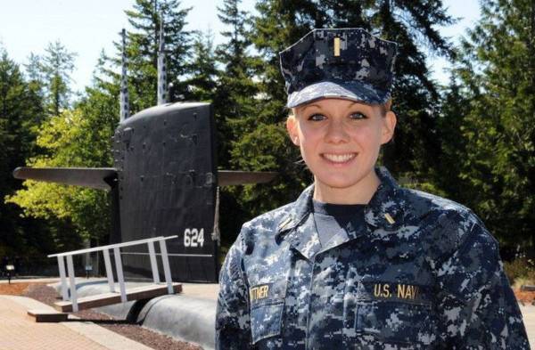 woman standing in front of submarine in military uniform